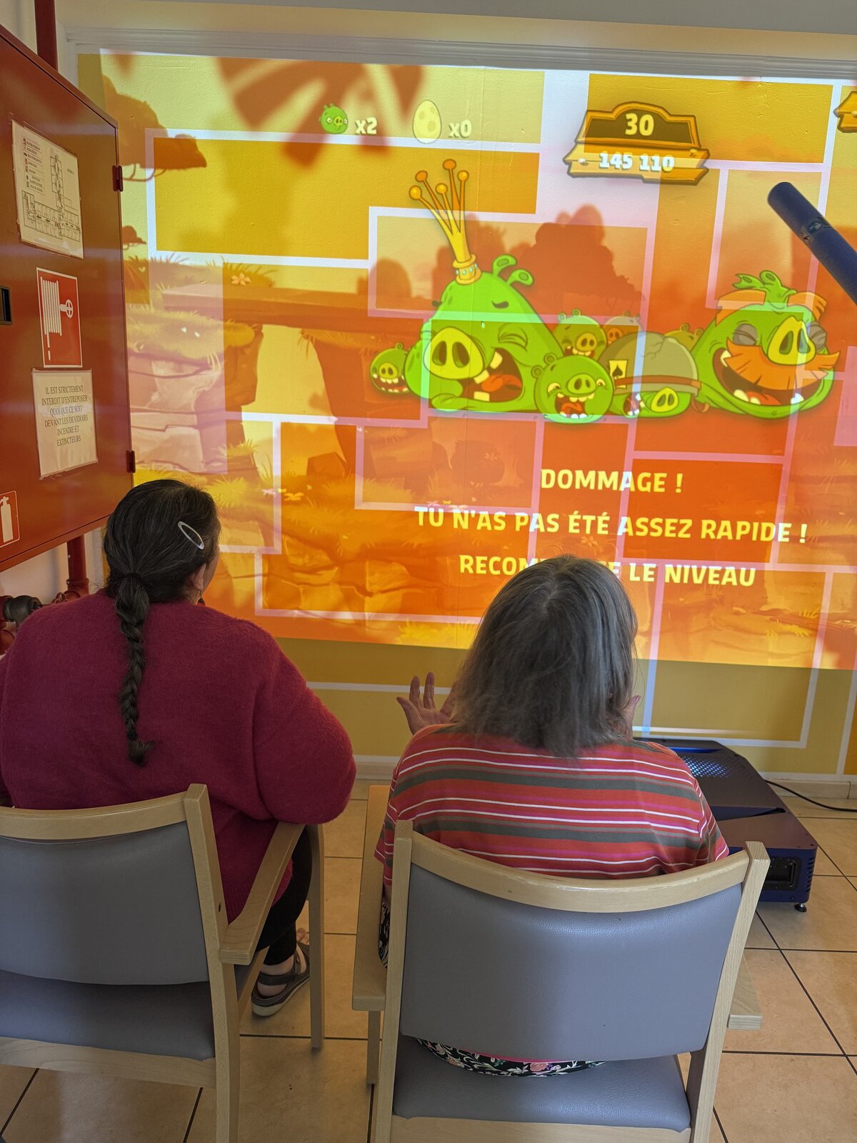 Résidents tapant la balle avec des frites de piscine devant le mur interactif